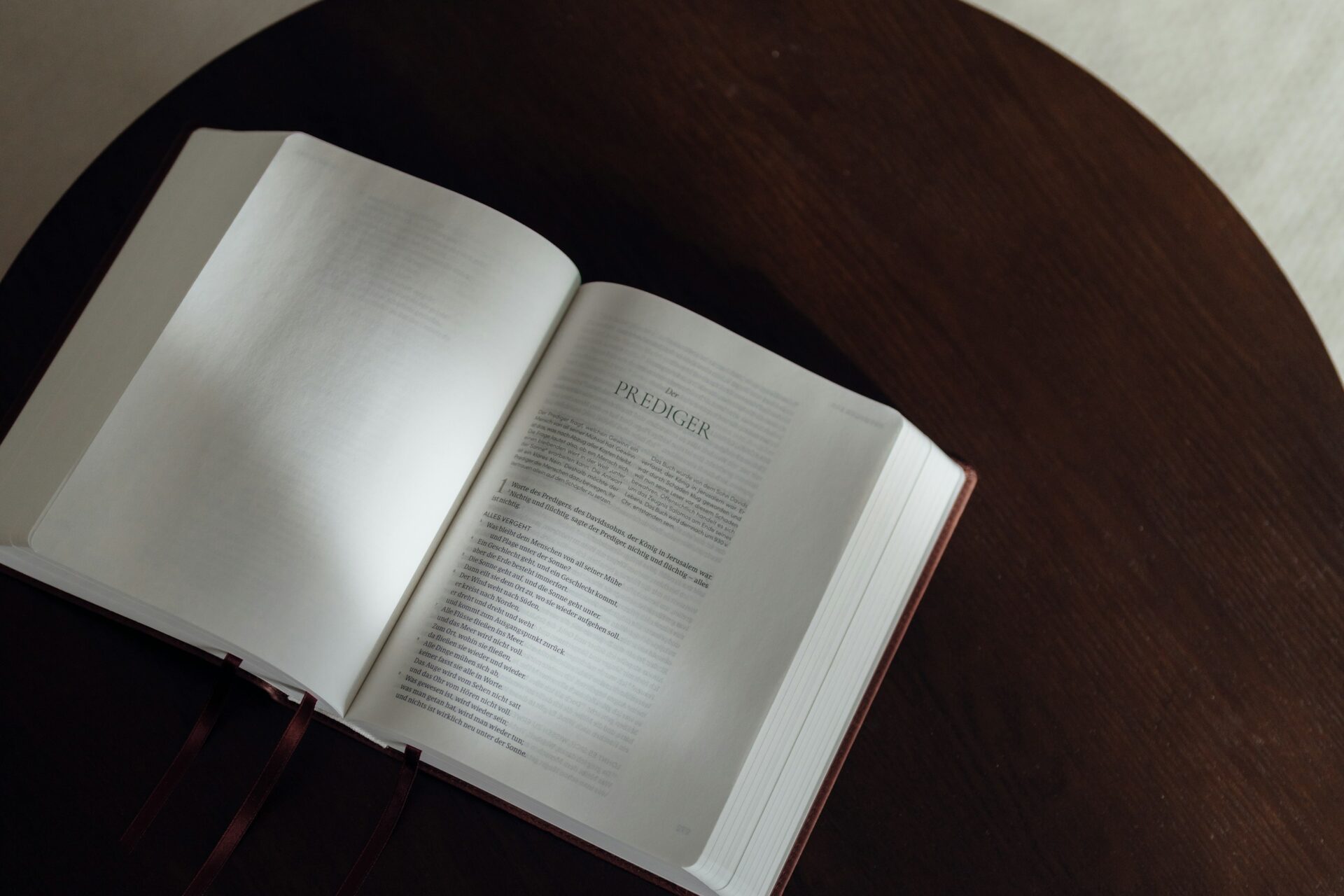 An open book rests on a dark wooden table.